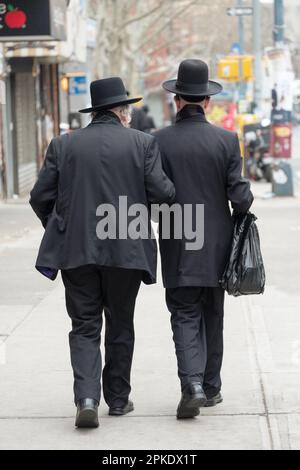 Due uomini ebrei anonimi camminano insieme braccio in braccio per il sostegno. A Brooklyn, New York. Foto Stock
