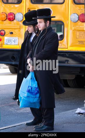 Due uomini ebrei chassidici, forse fratelli, aspettano un autobus su Lee Avenue a Brooklyn, New York. Foto Stock