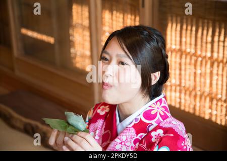 Donna in Kimono che mangia Kashiwa Mochi Foto Stock