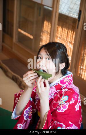 Donna in Kimono che mangia Kashiwa Mochi Foto Stock