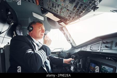 Vista laterale. Un pilota professionista è nel cockpit. Concezione del lavoro. Foto Stock