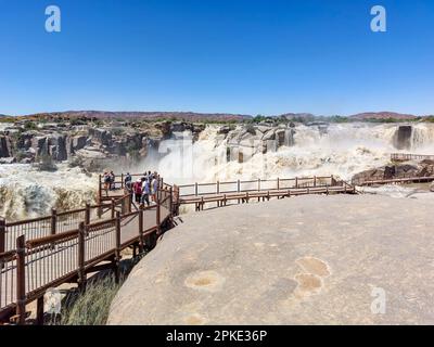 Augrabies National Park, Sudafrica - 25 febbraio 2023: Turisti in un punto di vista presso la cascata principale Augrabies nel fiume Orange. Il fiume è in Flo Foto Stock