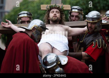 07 aprile 2023, Assia, Bensheim: Gesù (Julian Lux) è posto sulla croce durante la processione del Venerdì Santo. Circa 90 attori dilettanti e attrici in costumi storici sfilano attraverso il centro di Bensheim e rievocano le stazioni della Croce. La processione è organizzata dall'associazione 'Bensheim famiglie italiane e amici tedeschi'. L'evento si svolge per la prima volta dalla pandemia di Corona. Foto: Sebastian Christoph Gollnow/dpa Foto Stock