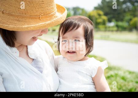 Bambino ridendo che è trasportato dalla madre Foto Stock