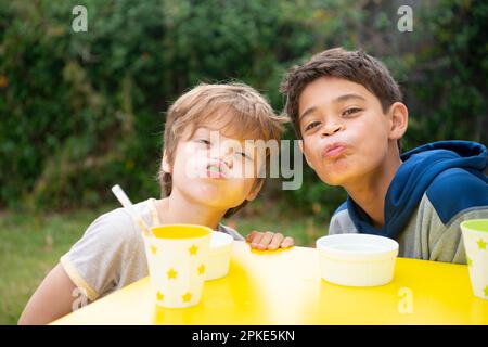 Fratelli che scherzano in giro con un sacco di uva in bocca Foto Stock