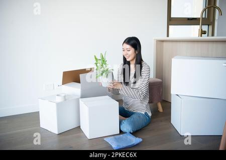 Donna che tiene vaso di piante circondato da cartone in movimento Foto Stock