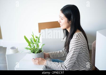 Donna che tiene un vaso di piante circondato da cartone in movimento Foto Stock