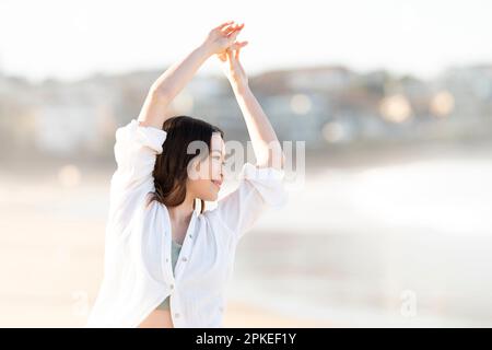 Donna che si allunga nel surf Foto Stock