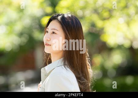 Vista laterale della donna sorridente con il verde sullo sfondo Foto Stock