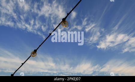 Gruppo di lampadine appese sui fili contro il cielo blu. Foto Stock