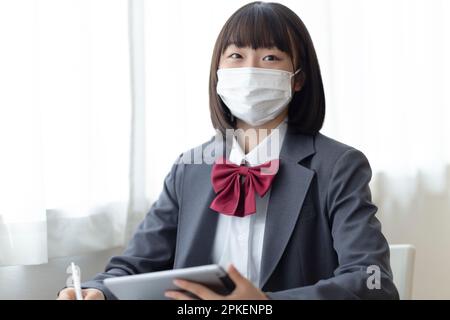 Ragazze della scuola superiore che indossano maschere in classe Foto Stock