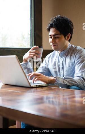 Uomini che usano i computer in un bar Foto Stock