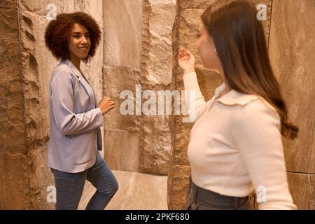 Donna responsabile della reception che parla con un bel cliente nel corridoio Foto Stock