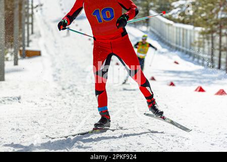 atleta maschile sciatore che corre in salita allo stadio di sci, gara di sport invernali Foto Stock