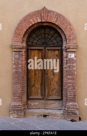 Porta ad arco ben indossata con porte doppie in legno in Toscana Foto Stock