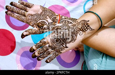 Una bella opera d'arte disegnata sulla mano di una sposa indiana con heena alle erbe in condizioni umide. Foto Stock