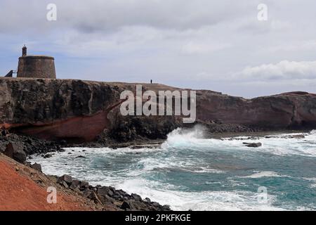 La cima della scogliera e le onde atlantiche che si infrangono alla torre dell'area di Torre del Aguila-Castillo De Las Coloradas, Lanzarote, Isole Canarie, Spagna Foto Stock