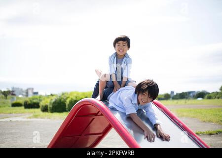 Ragazzi che giocano sullo scivolo al parco Foto Stock