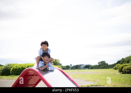 Ragazzi che giocano sullo scivolo al parco Foto Stock