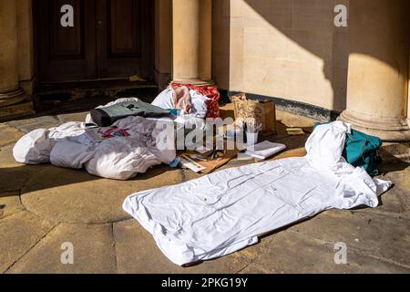 Biancheria da letto senza tetto nella porta della Chiesa a Bath, Inghilterra. Artista. Concetto di disuguaglianza sociale. Governo del Regno Unito. Economia del Regno Unito. La povertà nel Regno Unito. Foto Stock