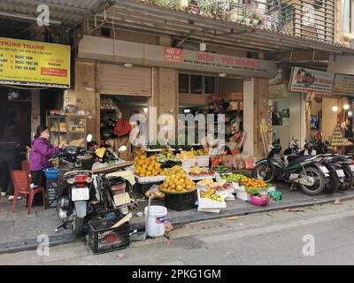 Hanoi, Vietnam. 26th Feb, 2023. Le donne sono occupate di fronte a un negozio che vende frutta e verdura in una strada nel quartiere vecchio. Credit: Alexandra Schuler/dpa/Alamy Live News Foto Stock