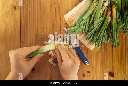 Donna cucina a mano su un tavolo di legno. Taglia verdure verdi. Vista dall'alto e primo piano. Foto Stock