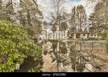 un'area cortile allagata con alberi e cespugli in primo piano, come si vede dall'altra parte del bordo dell'acqua Foto Stock