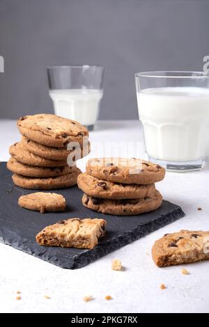 Biscotti al cioccolato con fiocchi d'avena su un asse da portata di ardesia e latte Foto Stock