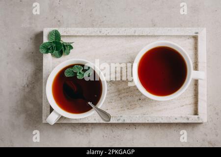 Due tazze di tè alla menta su un vassoio di marmo grigio Foto Stock