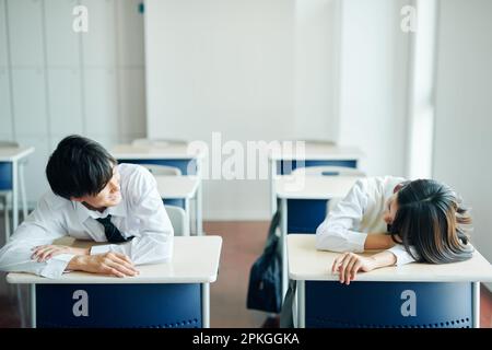 Uno studente di scuola superiore maschile e femminile che chiacchiera in classe durante la pausa Foto Stock