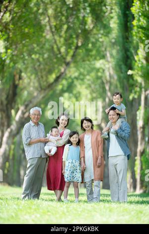 Una famiglia di tre generazioni sorridente ad una fila di pioppi Foto Stock