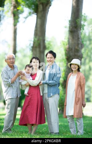 Una famiglia di tre generazioni sorride in una fila di alberi di pioppo Foto Stock