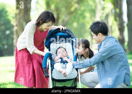 Genitori e bambini che guardano il bambino in passeggino Foto Stock