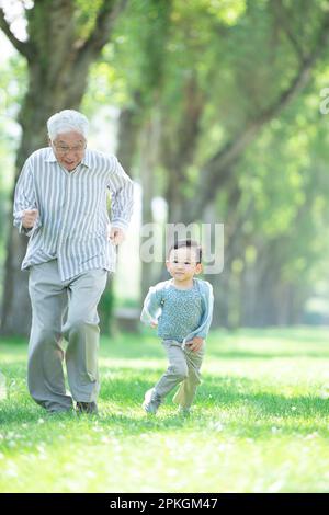 Nonno e nipoti che corrono lungo alberi di pioppo Foto Stock