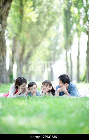 Famiglia sdraiata in una fila di alberi di pioppo Foto Stock