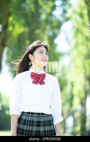 Studentessa sorridente ad una fila di alberi di pioppo Foto Stock