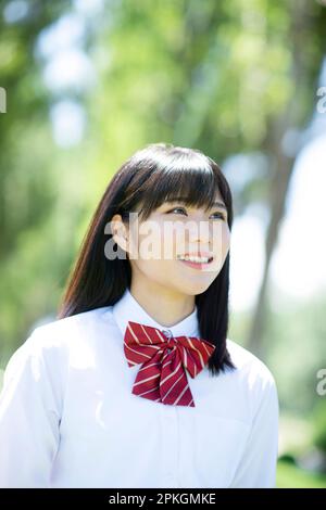 Studentessa sorridente ad una fila di alberi di pioppo Foto Stock