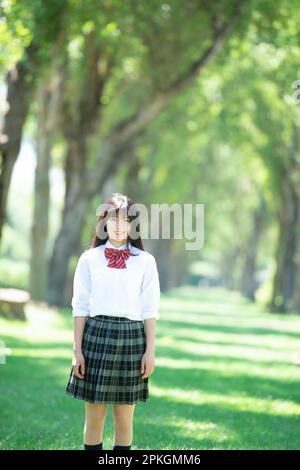 Studentessa sorridente ad una fila di alberi di pioppo Foto Stock