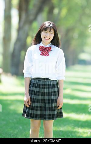 Studentessa sorridente ad una fila di alberi di pioppo Foto Stock