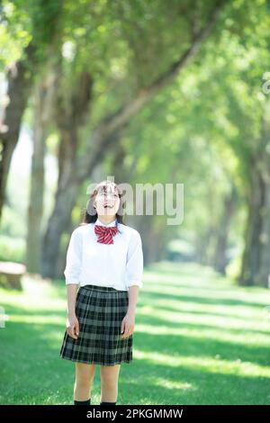 Studentessa sorridente ad una fila di alberi di pioppo Foto Stock