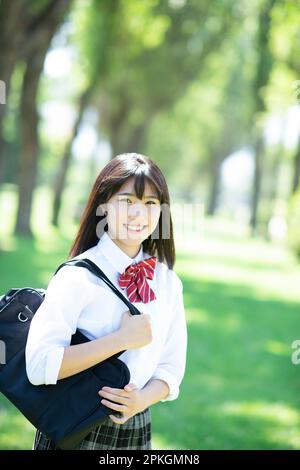 Studentessa sorridente ad una fila di alberi di pioppo Foto Stock