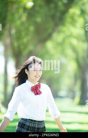 Studentessa sorridente ad una fila di alberi di pioppo Foto Stock