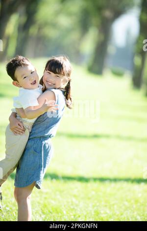 Una sorella e un fratello che si abbraccia in una fila di alberi di pioppo Foto Stock