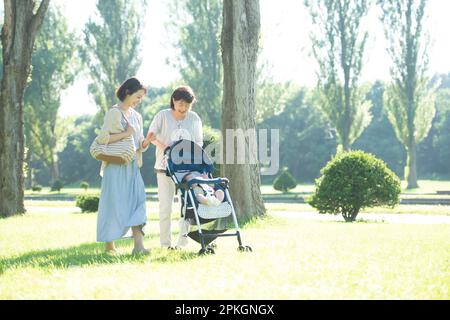 Una famiglia di tre generazioni passeggiando lungo il viale alberato di pioppo Foto Stock