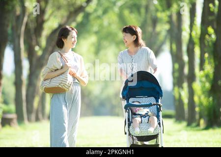Una famiglia di tre generazioni che fa una passeggiata lungo il viale alberato di pioppo Foto Stock