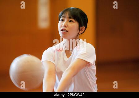 Le studentesse giocano a pallavolo in palestra Foto Stock