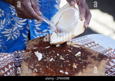 Un uomo che raccoglie la carne di una giovane noce di cocco appena raccolta Foto Stock