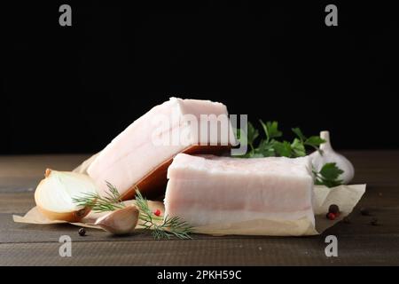 Gustoso maiale salato con erbe, cipolla e aglio su tavola di legno Foto Stock