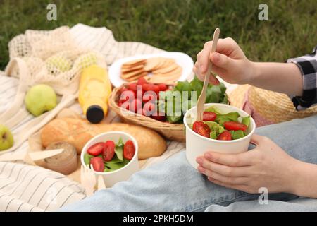 Ragazza che ha pic-nic su erba verde nel parco, primo piano Foto Stock