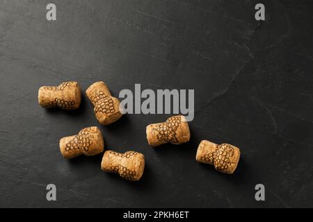 Tappi di vino frizzante con immagini d'uva su tavola nera, giacitura piatta. Spazio per il testo Foto Stock